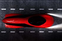 Ein rotes vollverschaltes Velomobil auf einem Fahrradweg.