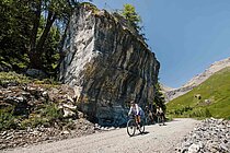 Gravelbiker überqueren eine Kiesstrasse in den Alpen.
