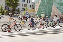 Kinder stehen mit Kinderfahrrädern auf einer grossen Treppe.
